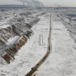 Carrière enneigée avec chemin et vue sur centrales électriques