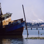 Épave de bateau rouillé près d'une usine