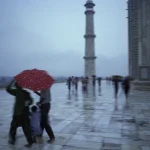Personnes avec parapluies près d'un minaret sous la pluie