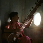 Musicien jouant du sitar près d'une fenêtre