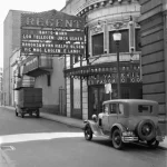 Façade d'un cinéma vintage avec voitures classiques dans la rue