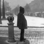 Personne en manteau observant une place enneigée en ville
