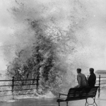 Deux personnes sur un banc face à une forte vague