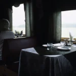 Femme seule dans un wagon de train vide, contemplant le paysage à travers la fenêtre