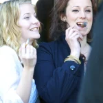 Deux femmes jeunes fument et sourient ensemble à l'extérieur