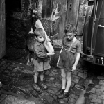 Enfants portant du pain dans une rue pavée