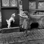 Fillette et Chien Jouant Devant Une Porte
