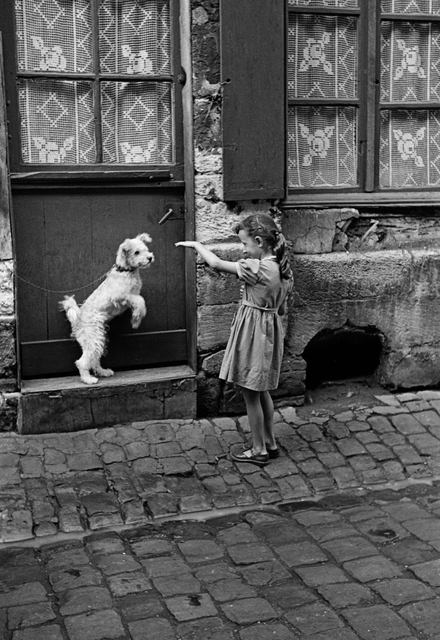 AKG1090159.webp Fillette et Chien Jouant Devant Une Porte – Image 1