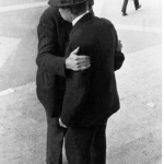 Deux Hommes en Chapeau Discutant dans la Rue