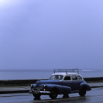 Voiture classique roulant sous un ciel couvert au bord de la mer