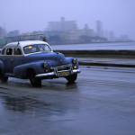 Voiture ancienne roulant sur une route mouillée près de la mer