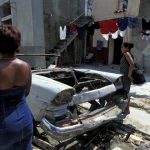 Deux femmes passant devant une vieille voiture dans une ruelle