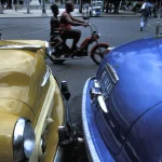 Voitures Anciennes et Cyclomoteur Dans une Rue Animée