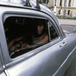 Homme dans une voiture argentée devant un bâtiment historique
