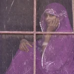 Femme en sari violet regardant par la fenêtre