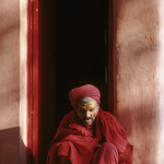 Homme lisant un livre sacré dans l'entrée d'un bâtiment