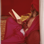 Moine lisant un livre sacré en vêtement rouge