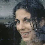 Sourire derrière une vitre mouillée
