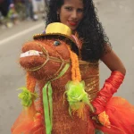 Femme en robe colorée avec marionnette de cheval lors d'un carnaval