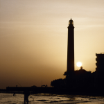 Coucher de soleil sur un phare avec un pêcheur