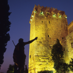 Tour médiévale illuminée avec statue au crépuscule