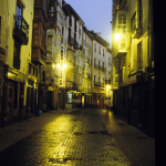 Rue pavée nocturne avec lampadaires et bâtiments historiques