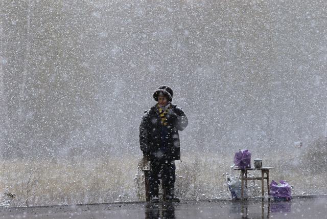 AKG1310943.webp Personne debout sous la neige avec des sacs à côté – Image 1