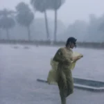 Personne marchant sous la forte pluie avec des palmiers en arrière-plan