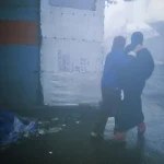 Deux femmes sous un parapluie transparent marchant dans une rue brumeuse