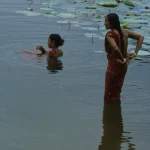 Deux femmes dans un plan d'eau avec des nénuphars