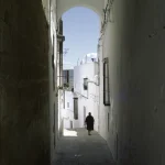 Porte en arcade d'une ruelle étroite avec une femme marchant au loin