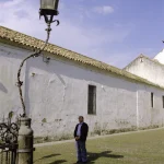 Homme regardant un vieux lampadaire dans une rue pavée