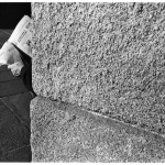 Lecture de journal derrière un mur en pierre