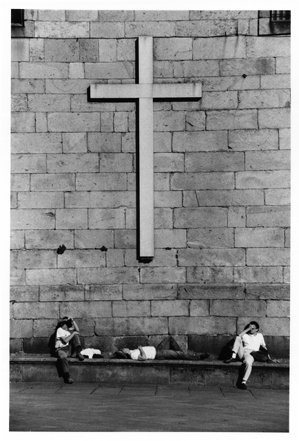AKG1349817.webp Croix sur un mur de pierre avec trois personnes se reposant à l'extérieur – Image 1