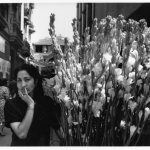 Femme avec des fleurs dans une rue animée en noir et blanc