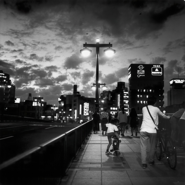 AKG1426383.webp Soirée en ville avec piétons et cyclistes – Image 1