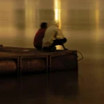 Deux personnes assises sur un quai flottant à la nuit tombée