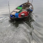 Pêcheur seul sur un bateau traditionnel en mer calme