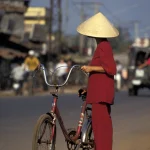 Femme asiatique avec chapeau traditionnel et vélo