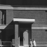 Deux enfants marchant devant un bâtiment en brique