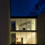 Maison moderne à façade vitrée illuminée de nuit