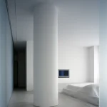Intérieur minimaliste avec colonne centrale blanche et lit