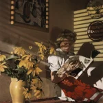 Femme lisant à côté d'un vase de fleurs jaunes