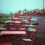 Chaises et tables colorées en extérieur un jour de pluie