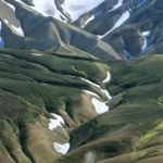 Vallée montagneuse avec neiges éternelles et rares zones verdoyantes