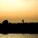 Pêcheur au coucher du soleil sur une jetée