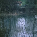 Cabane au bord d'un lac calme en hiver