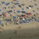 Vue aérienne d'une plage animée avec des parasols et des transats