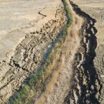 Fissure asséchée avec végétation et vue sur lac salé