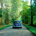 Voiture ancienne roulant sur une route forestière